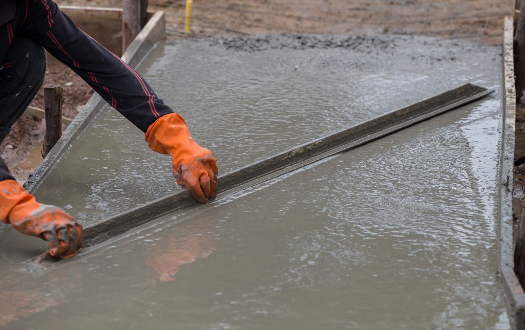 Wet screed being smoothed over concrete flooring.